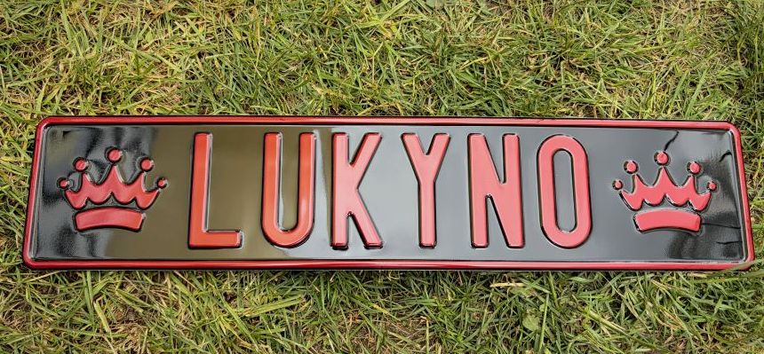 LUKYNO — čierna tabuľka s červeným razeným písmom a korunkami